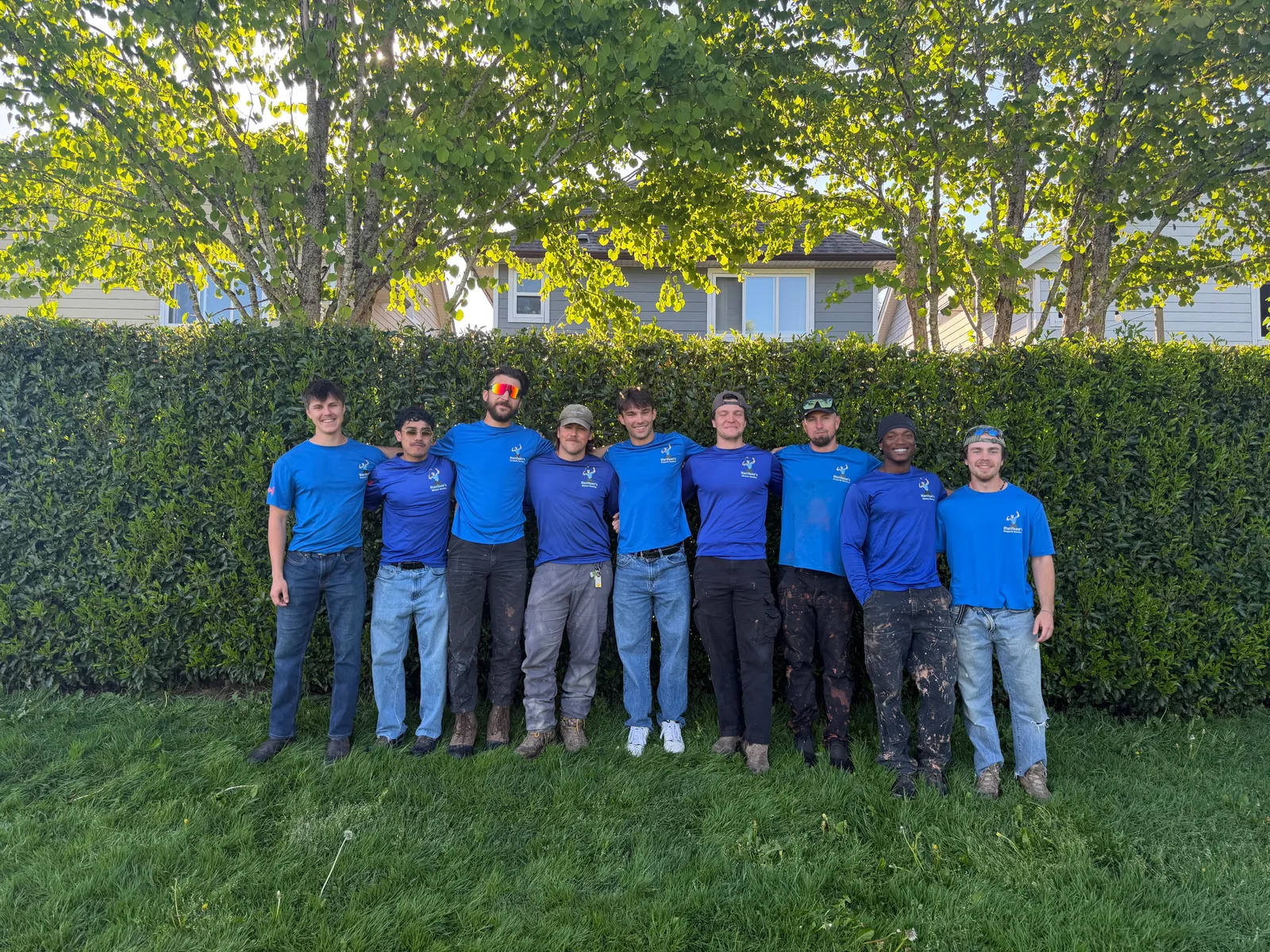 The Harrison’s Property Services team standing together outdoors in their blue work shirts